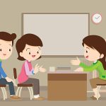 Parent meeting with teacher in classroom.